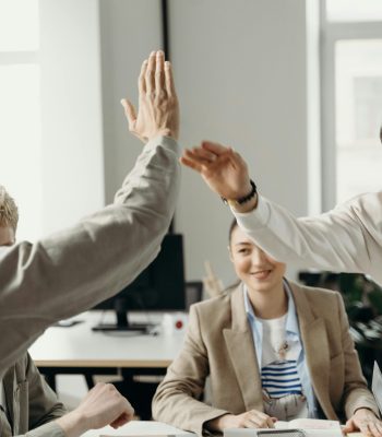 Colleagues in an office exchanging a high five, symbolizing teamwork and success.